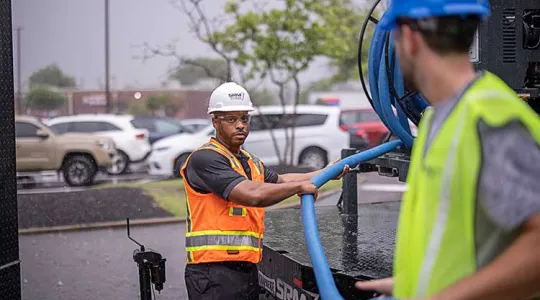SRM employees with hose hooked up to truck