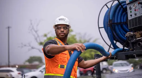 SRM worker holding hose from truck